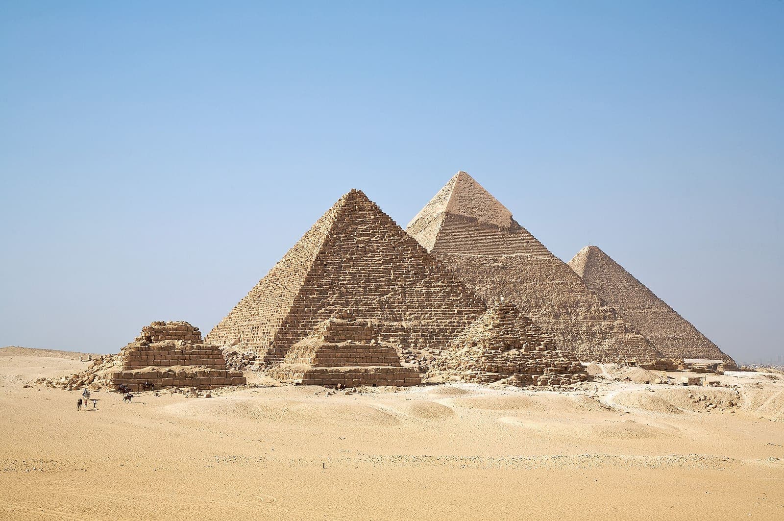 The pyramids at Giza standing in desert sand under a clear sky.